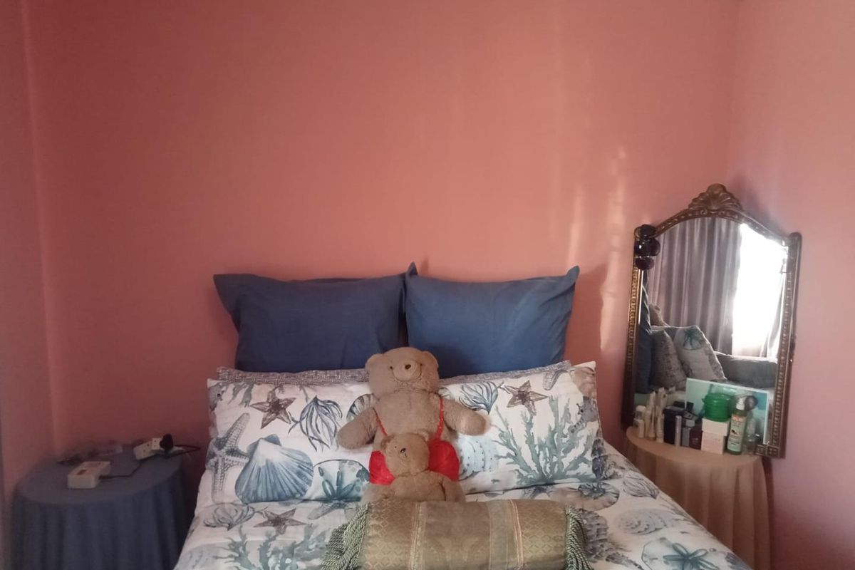 A bedroom featuring pink painted walls and a central bed placement.