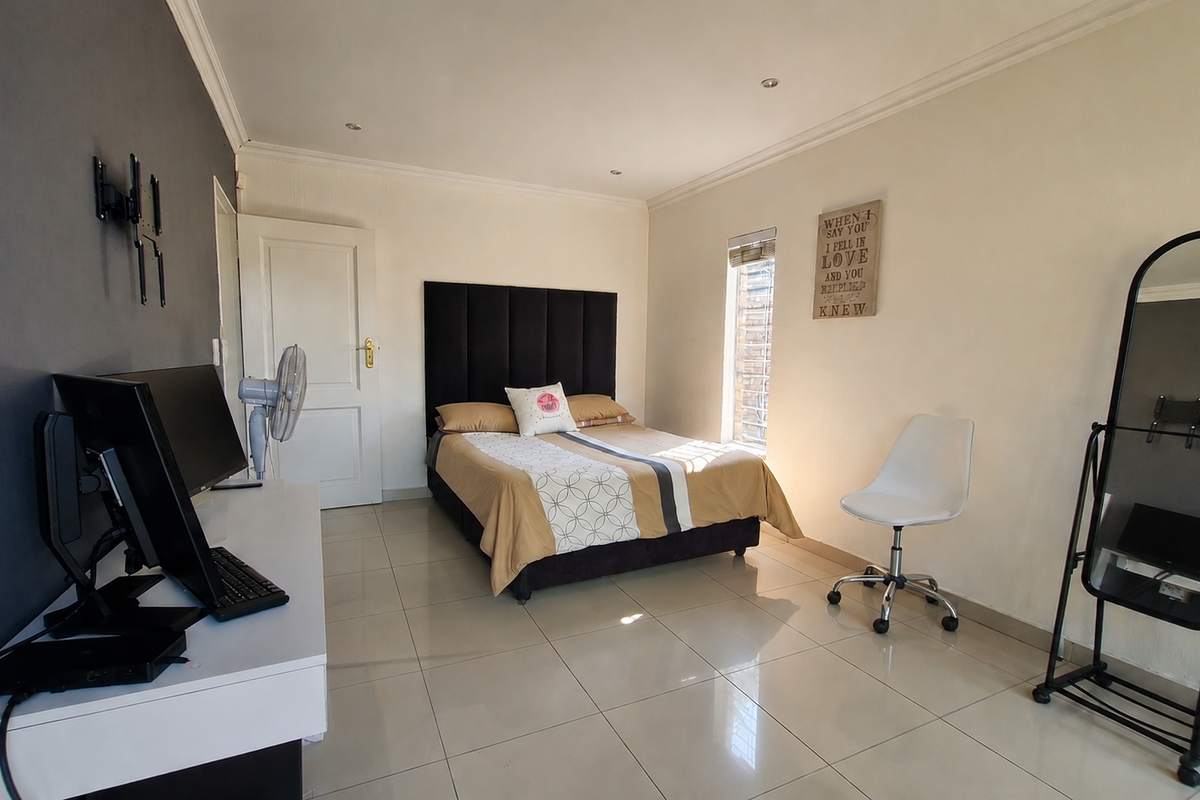 A well-maintained bedroom featuring neutral walls, a dark accent wall, tiled flooring, and recessed downlighting.