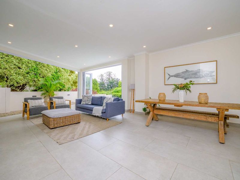 Spacious open-plan living area featuring large format floor tiles, recessed downlights, and seamless indoor-outdoor flow through expansive bi-fold doors.