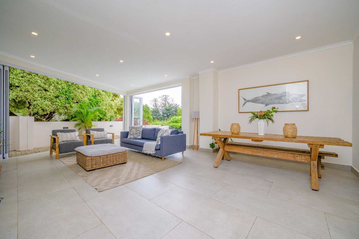 Spacious open-plan living area featuring large format floor tiles, recessed downlights, and seamless indoor-outdoor flow through expansive bi-fold doors.