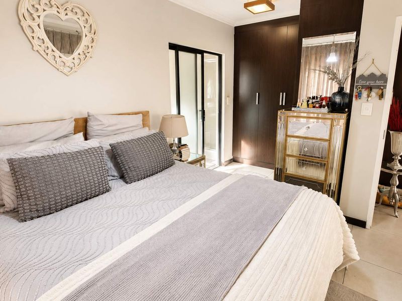 A well-maintained bedroom featuring dark wood built-in cupboards, tiled flooring, and a sliding glass door providing access to an outdoor area.