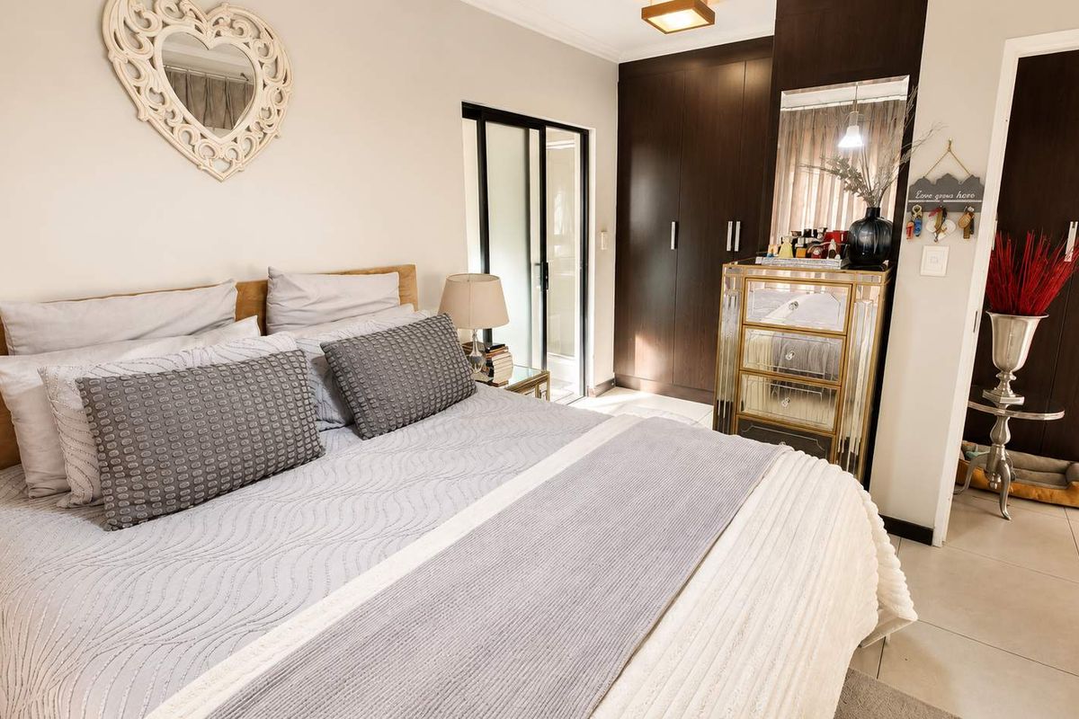A well-maintained bedroom featuring dark wood built-in cupboards, tiled flooring, and a sliding glass door providing access to an outdoor area.