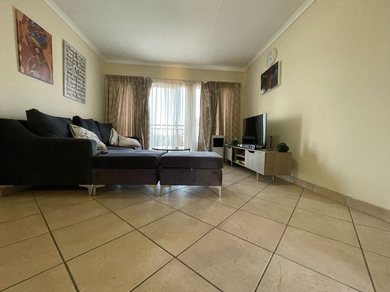 A comfortable living room featuring tiled flooring and a sliding glass door providing access to an outdoor area.