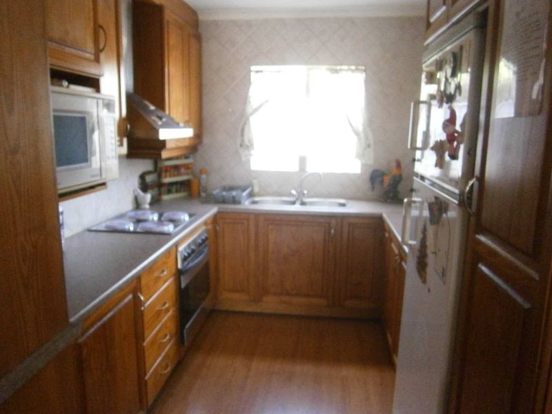A functional kitchen featuring traditional wooden cabinetry, built-in appliances, and a double sink, offering a classic layout with ample storage space.
