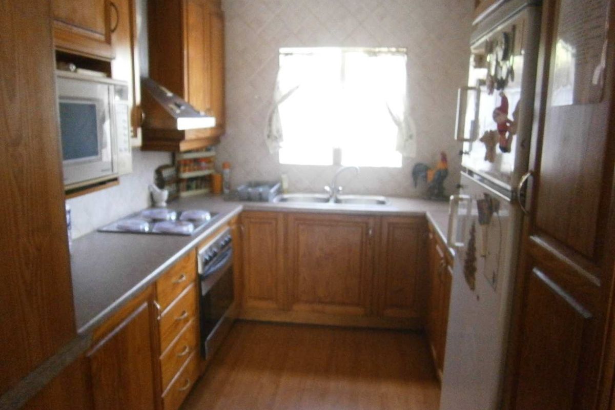 A functional kitchen featuring traditional wooden cabinetry, built-in appliances, and a double sink, offering a classic layout with ample storage space.
