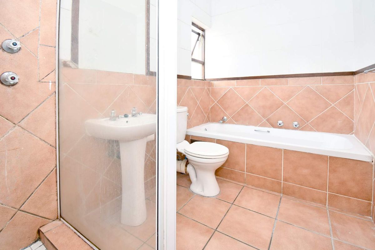A functional bathroom featuring a pedestal sink, a built-in bathtub, and a separate shower enclosure with tiled walls and flooring.