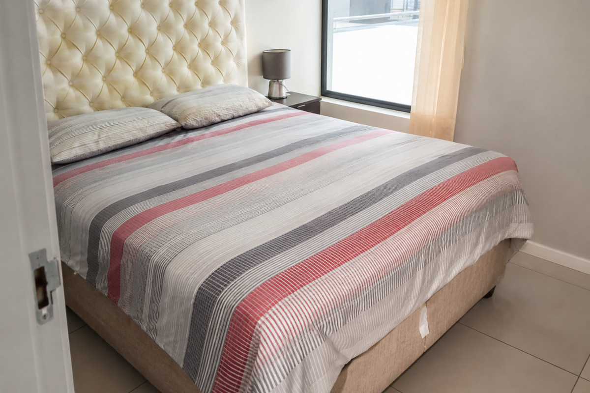 A well-maintained bedroom featuring neutral tiled flooring and a large window that allows for natural light.