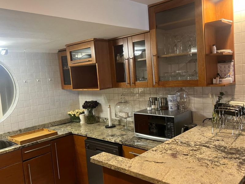 A functional kitchen featuring granite countertops, wooden cabinetry, a tiled backsplash, and a unique circular window, providing a classic aesthetic.