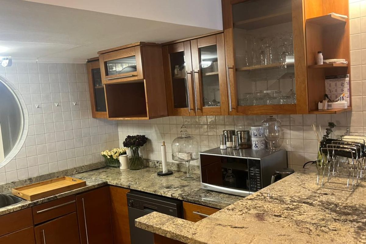 A functional kitchen featuring granite countertops, wooden cabinetry, a tiled backsplash, and a unique circular window, providing a classic aesthetic.