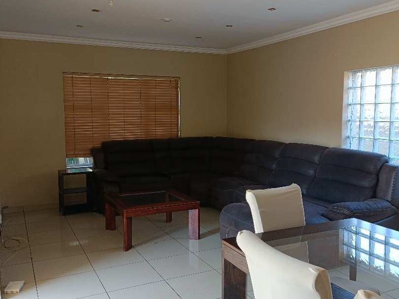 Open plan living and dining area featuring tiled flooring, a glass block window, and recessed lighting, requiring minor ceiling repairs.