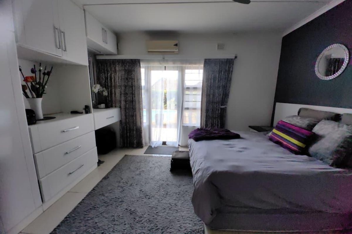 A well-maintained bedroom featuring built-in cabinetry, a wall-mounted air conditioning unit, and sliding glass doors providing access to the outdoor area.