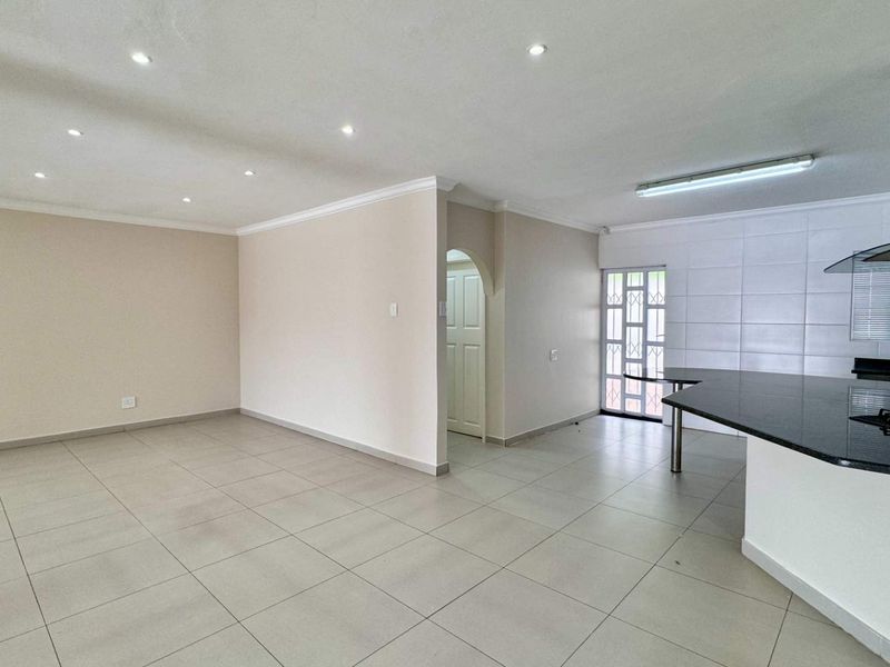 Spacious open-plan living area featuring tiled floors, recessed lighting, and a modern kitchen with granite countertops and a built-in gas hob.