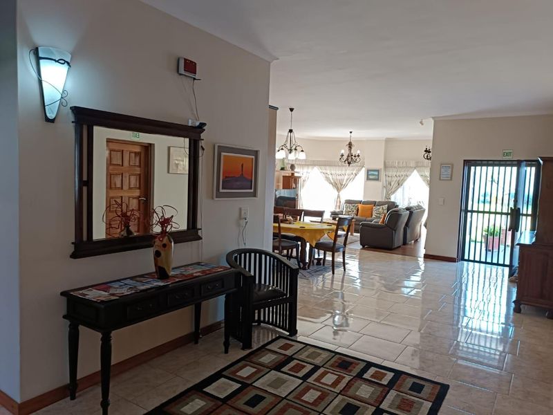 Spacious open-plan living and dining area featuring neutral tiled flooring, ample natural light, and direct access to an exterior security gate.