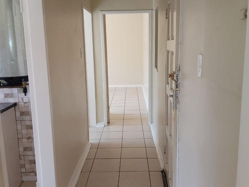 A functional hallway featuring tiled flooring and access to adjacent rooms, presenting a neutral canvas for potential interior updates.