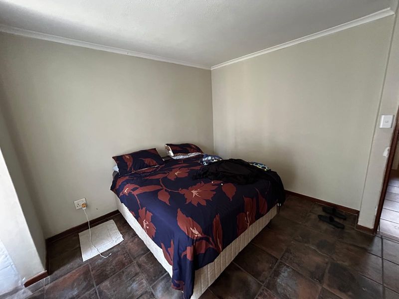A bedroom featuring tiled flooring and neutral wall finishes, providing a functional space for rest.