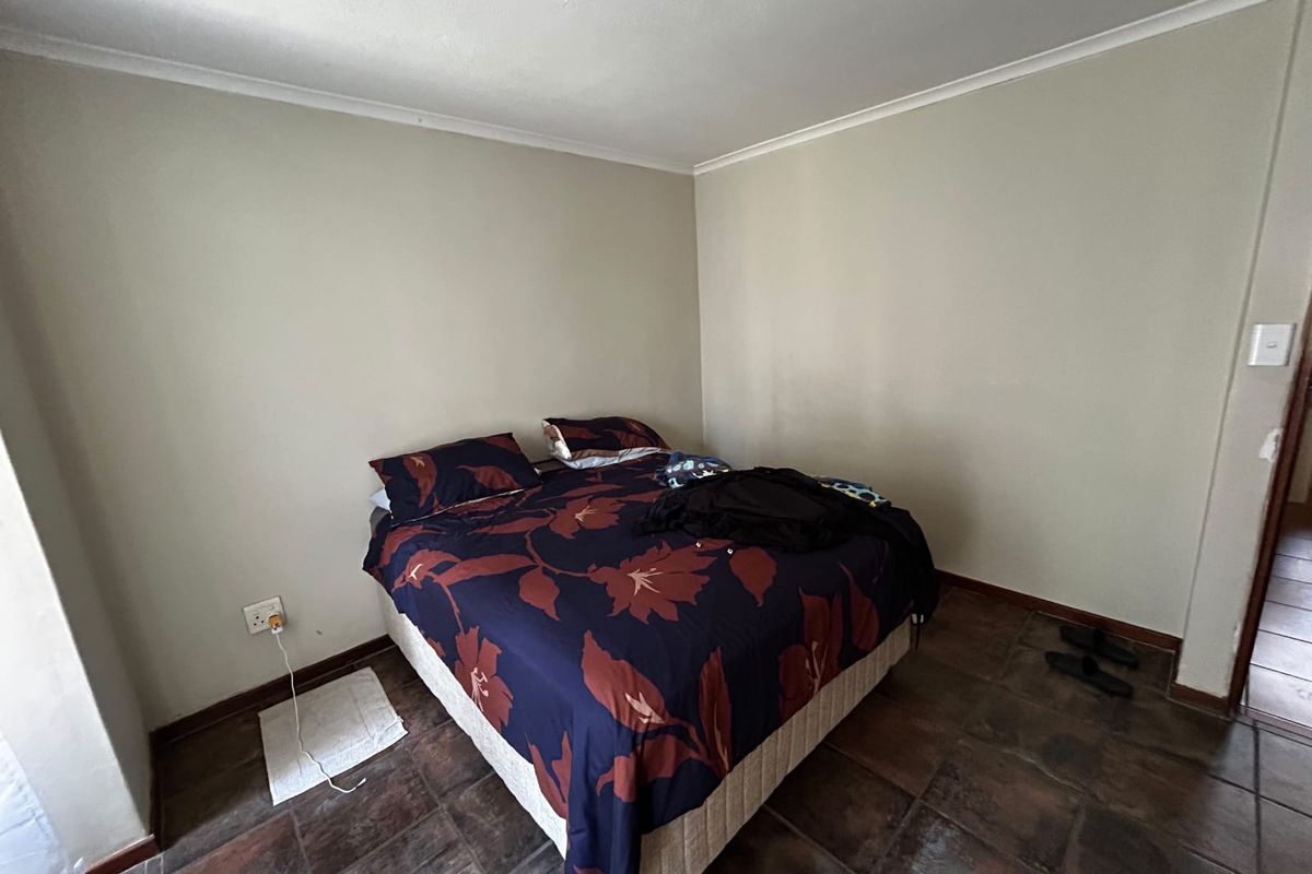 A bedroom featuring tiled flooring and neutral wall finishes, providing a functional space for rest.