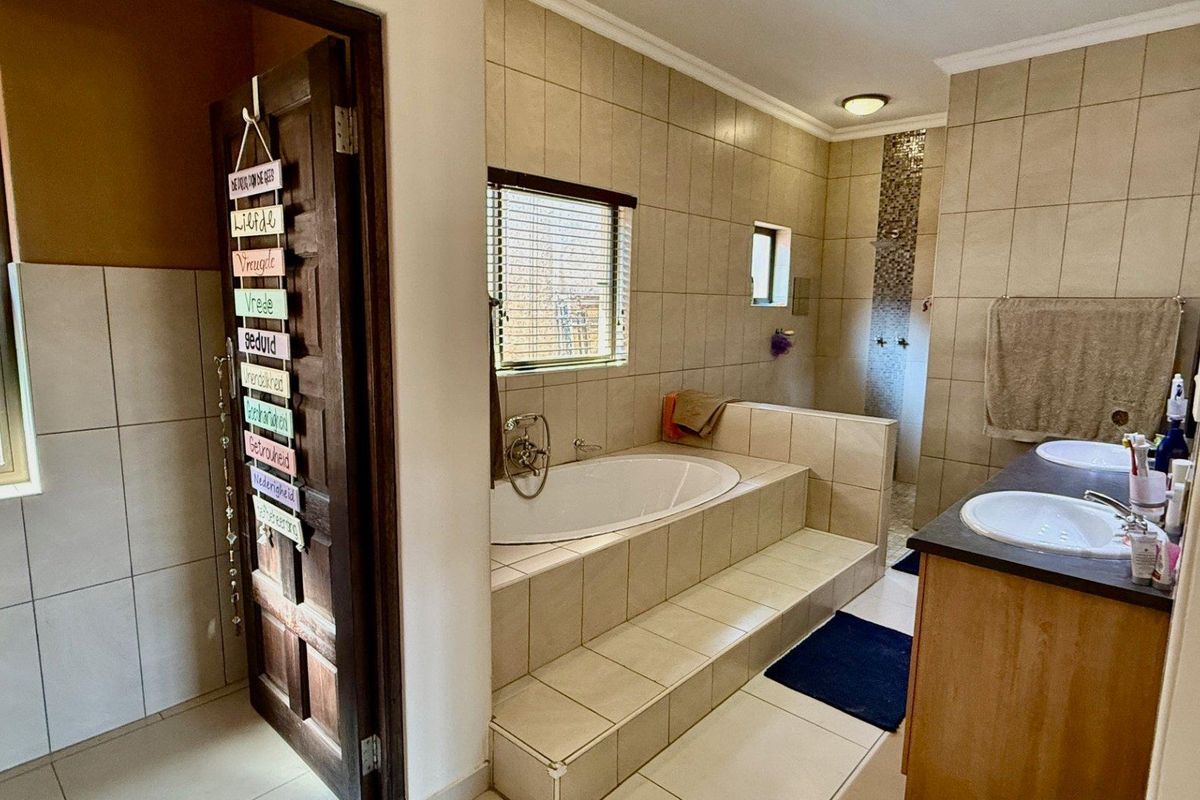 Spacious bathroom featuring a built-in tiled bathtub, dual vanity with integrated sinks, and a separate walk-in shower area with neutral wall tiling.