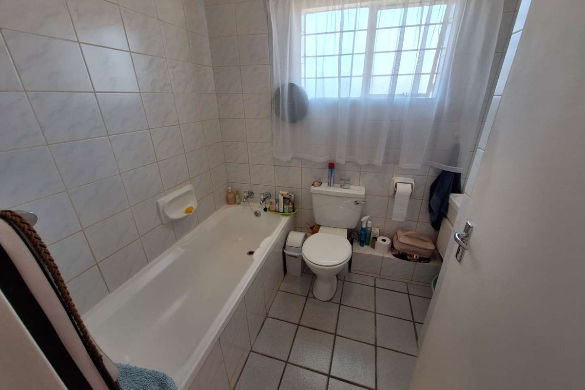 A functional bathroom featuring a standard bathtub, toilet, and tiled finishes throughout, offering a clean and practical space.