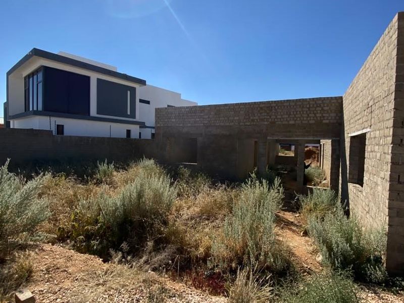 An unfinished residential construction site showing exposed brickwork and structural walls in a state of early development.