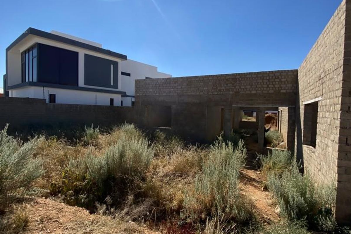An unfinished residential construction site showing exposed brickwork and structural walls in a state of early development.