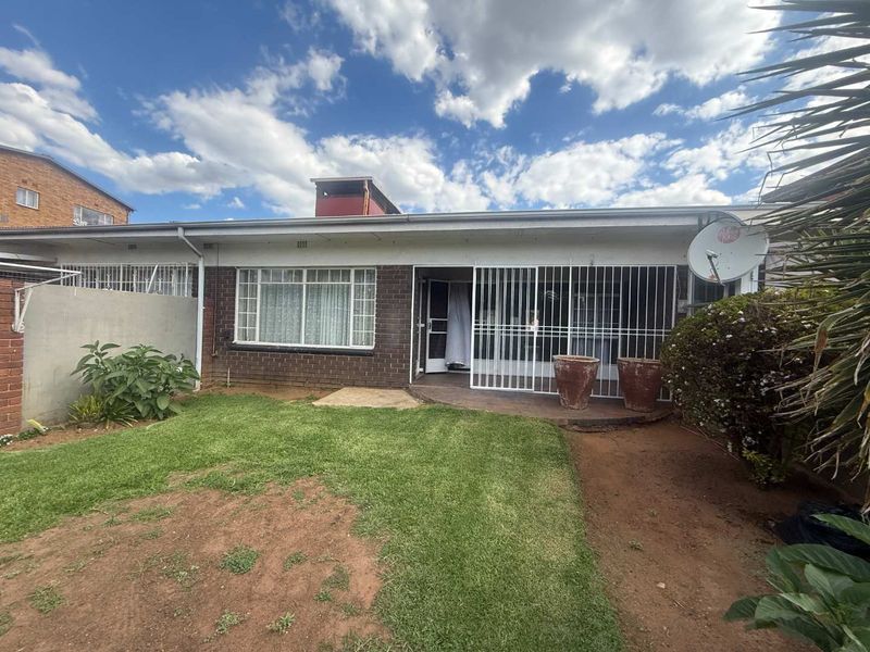 Rear view of the townhouse featuring a brick facade, security gates, and a small private garden area.