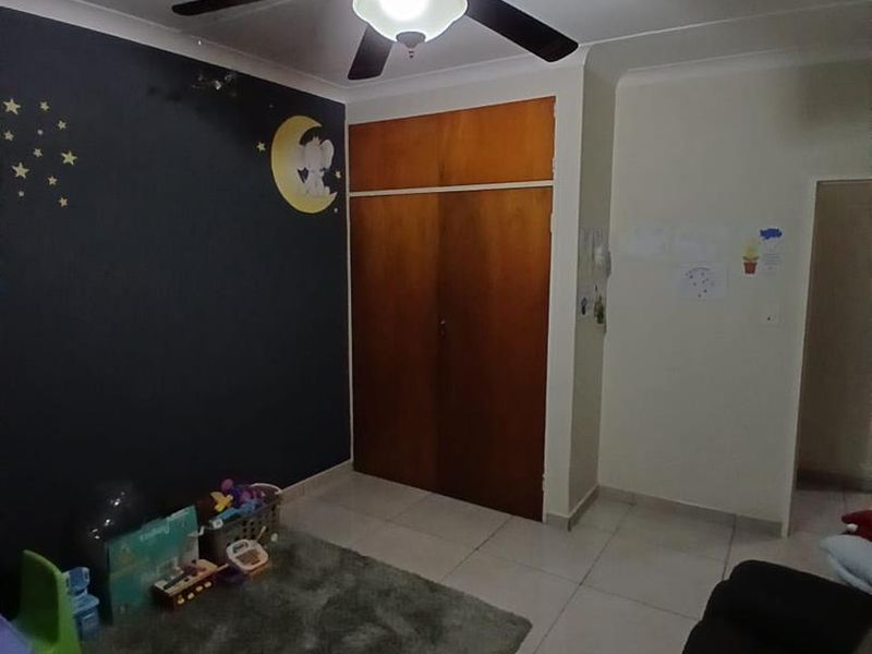 A bedroom featuring tiled flooring, a ceiling fan, and a built-in wooden cupboard with overhead storage.