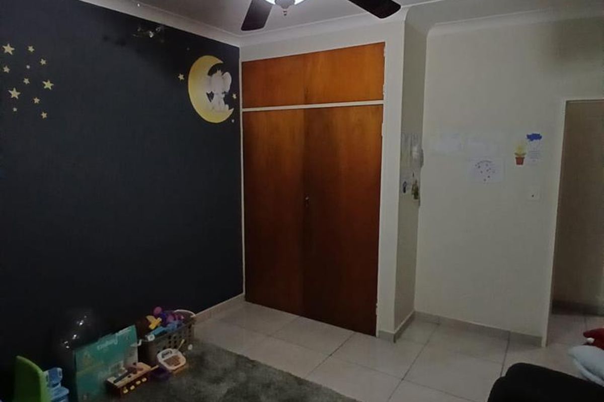 A bedroom featuring tiled flooring, a ceiling fan, and a built-in wooden cupboard with overhead storage.