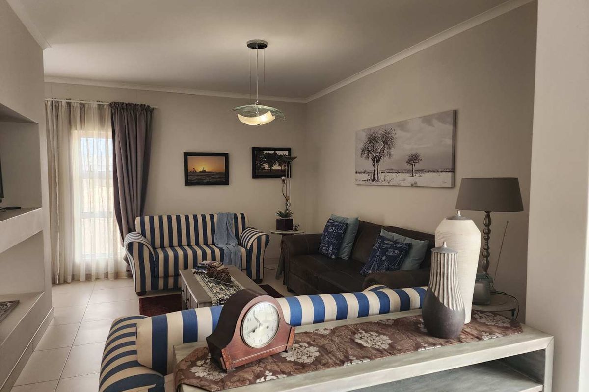 A comfortable living room featuring tiled flooring, neutral wall tones, and a built-in fireplace, creating a warm and inviting atmosphere.