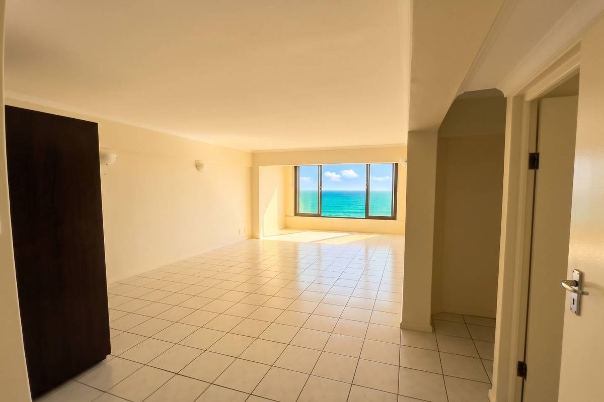 Spacious, empty living area featuring tiled flooring, built-in storage, and a large window offering a clear ocean view.