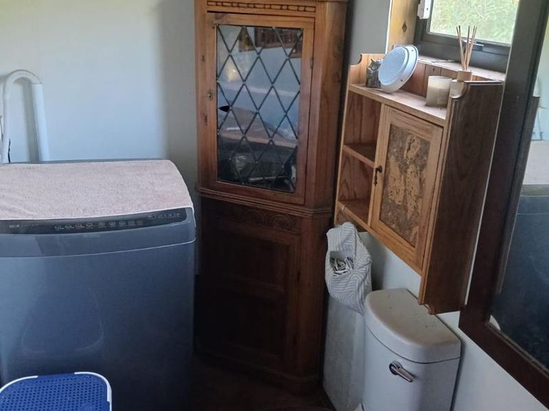 A small utility space featuring a toilet and window, currently utilized as a laundry area.
