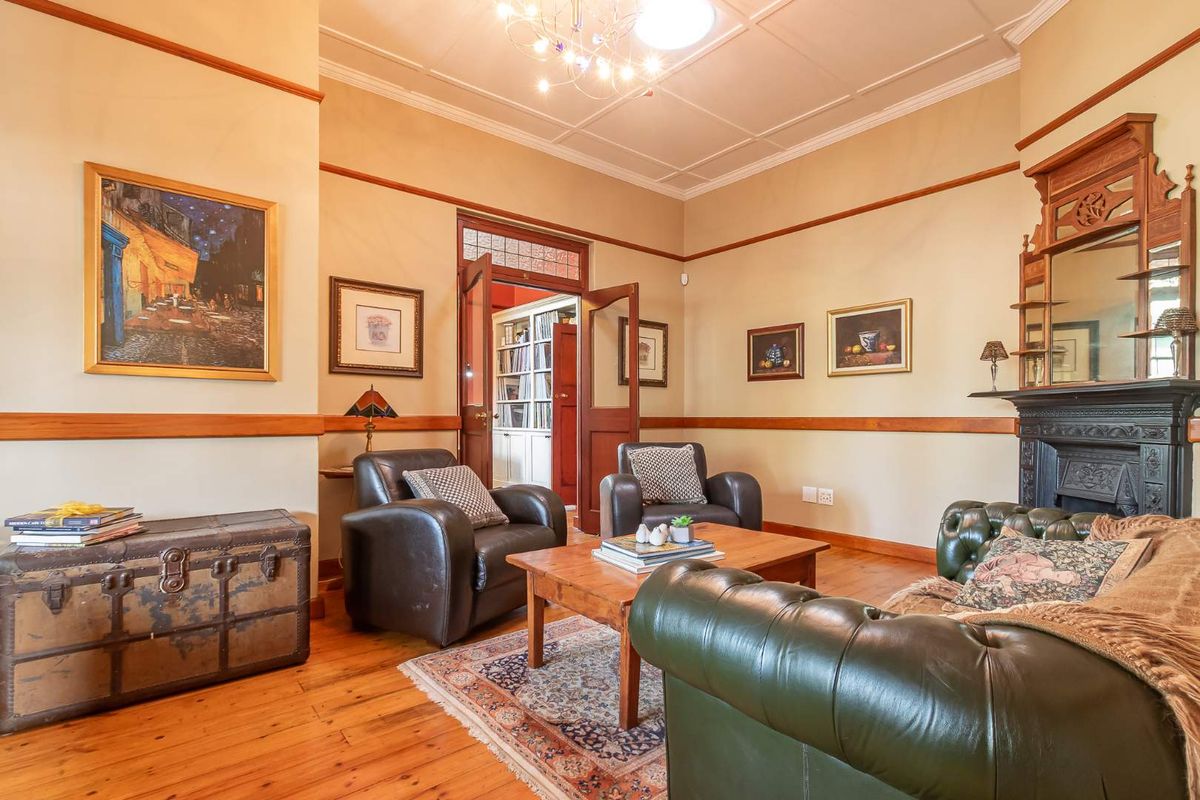 A classic living room featuring original hardwood flooring, a decorative cast iron fireplace, and traditional architectural details including picture rails and a coffered ceiling.