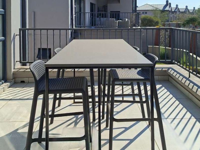 A spacious outdoor balcony featuring tiled flooring and a secure metal balustrade, offering a functional area for outdoor relaxation.