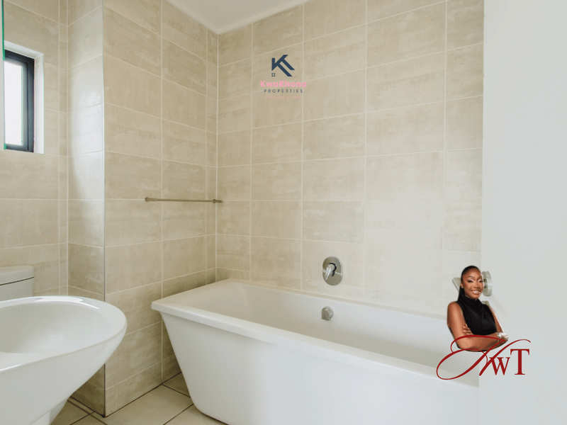 A clean, modern bathroom featuring neutral wall tiles, a white bathtub with a chrome mixer tap, and a basin.