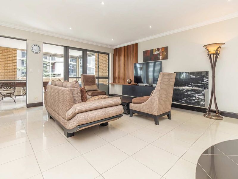 Spacious living room featuring polished tile flooring, recessed lighting, a decorative timber slat wall, and integrated marble-topped cabinetry with access to an enclosed balcony.
