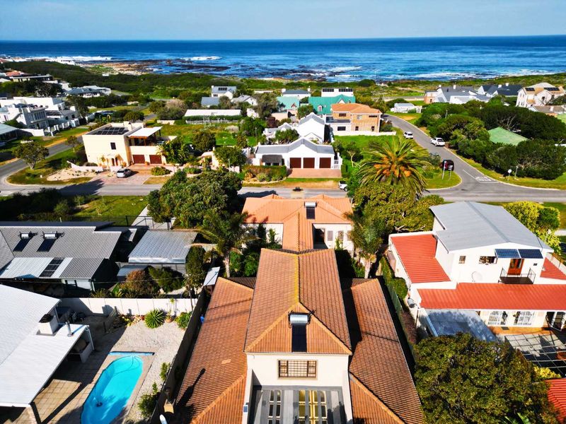 Aerial view of the property showcasing the tiled roof, solar water heater, private swimming pool, and surrounding coastal neighborhood landscape.