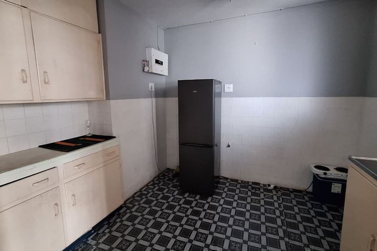 A functional kitchen space featuring built-in cabinetry, tiled splashbacks, and an electrical distribution board, offering potential for modernization and cosmetic updates.
