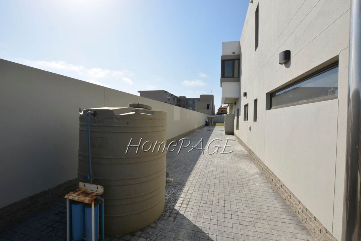 Side exterior walkway featuring paved flooring, a large water storage tank, and an external water filtration system along the building wall.