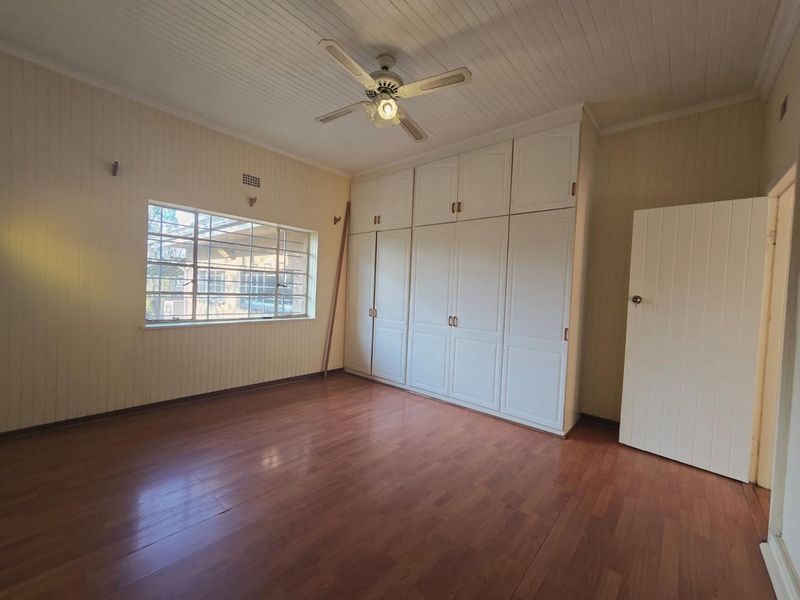 Spacious bedroom featuring built-in cupboards, timber panelled walls and ceiling, and laminate flooring, offering a neutral canvas for potential updates.