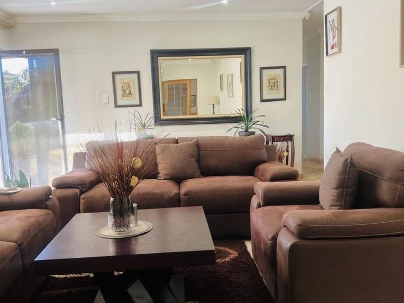 A comfortable living room featuring tiled flooring, coved ceilings, and a sliding glass door providing natural light and access to the exterior.