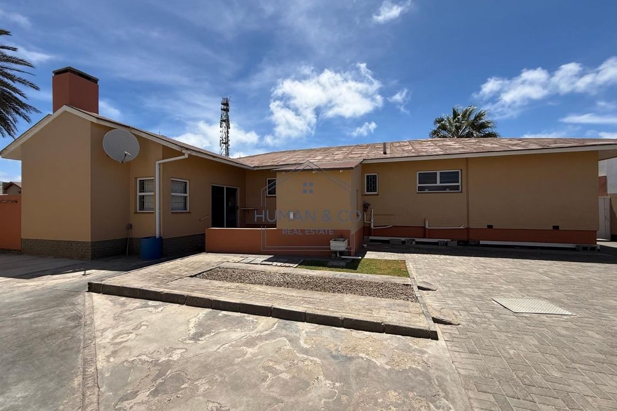 Rear exterior view of the property featuring a paved courtyard area, concrete patio, and access to the building structure.