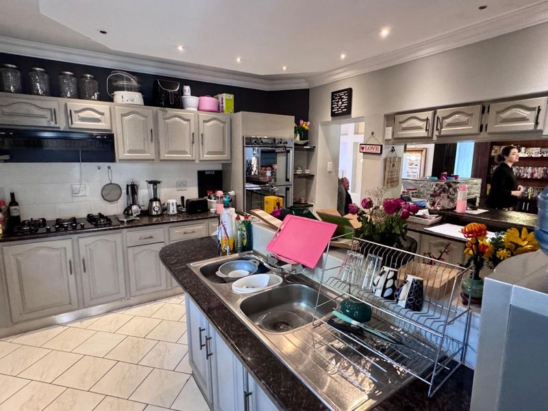 A functional kitchen featuring light-toned cabinetry, dark granite countertops, a double-basin sink, and built-in oven, offering a practical layout for daily meal preparation.
