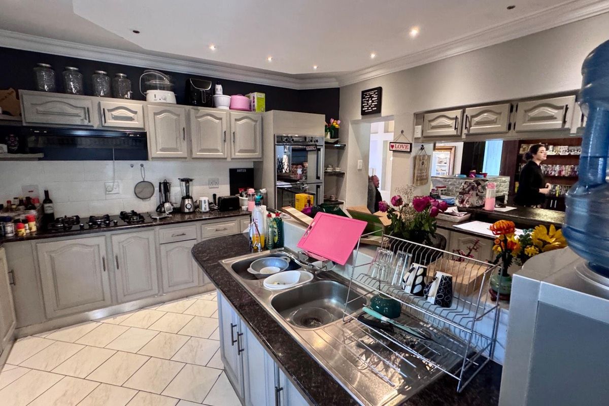 A functional kitchen featuring light-toned cabinetry, dark granite countertops, a double-basin sink, and built-in oven, offering a practical layout for daily meal preparation.