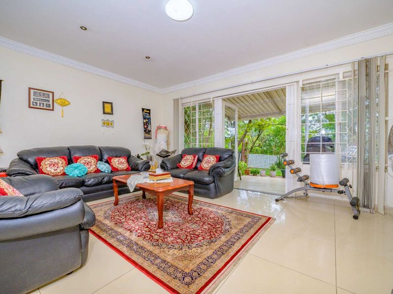 Spacious living room featuring tiled flooring, recessed lighting, and large sliding glass doors providing direct access to the outdoor patio area.