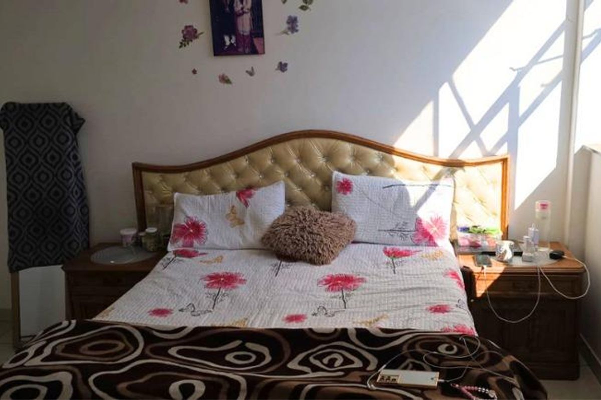 A functional bedroom featuring tiled flooring and a built-in wardrobe, benefiting from natural light through the side window.