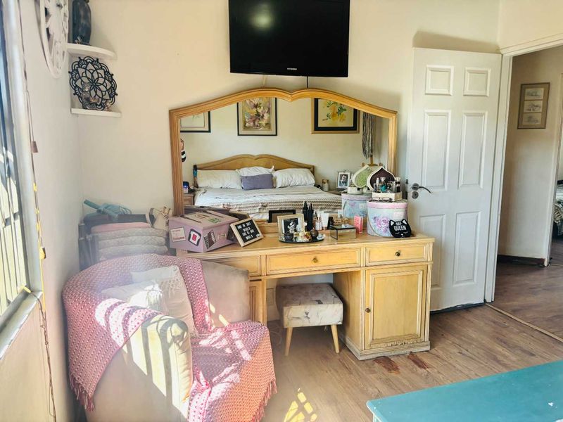 A bedroom featuring laminate flooring and a wall-mounted television, providing a functional space with neutral wall finishes.