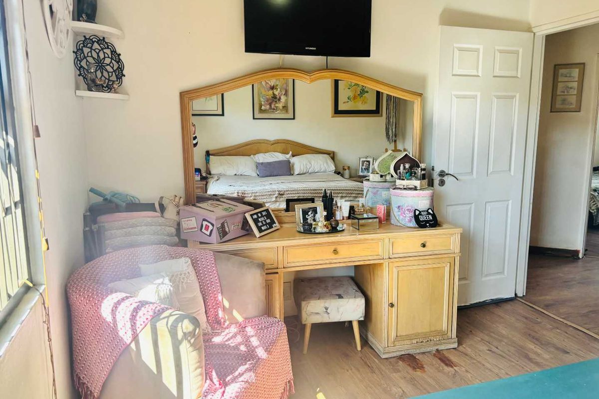 A bedroom featuring laminate flooring and a wall-mounted television, providing a functional space with neutral wall finishes.