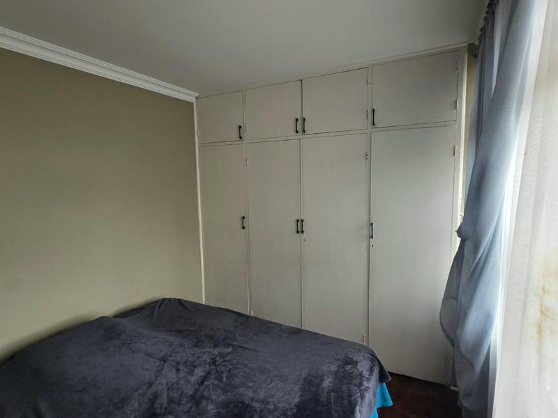 A bedroom featuring floor-to-ceiling built-in cupboards and decorative cornice detailing.