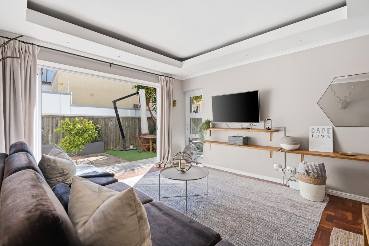 Bright living room featuring parquet flooring, recessed ceiling lighting, and large sliding glass doors opening onto a private outdoor patio area.