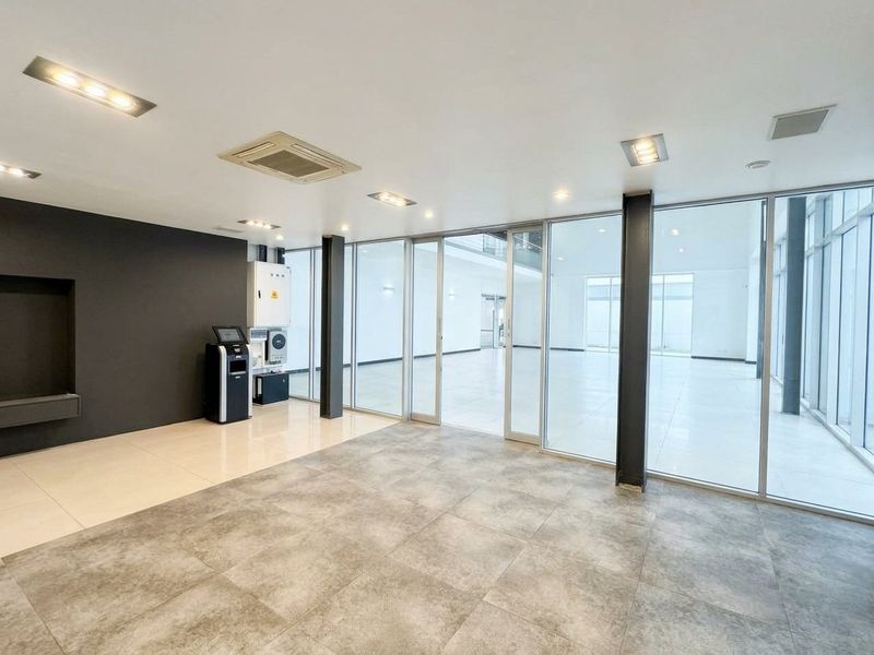 Spacious open-plan commercial area featuring modern tiled flooring, floor-to-ceiling glass partitions, and integrated ceiling lighting, suitable for a versatile office or showroom layout.