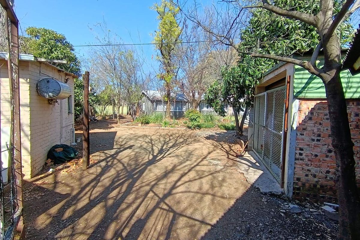 Rear yard area featuring a brick structure, external geyser, and chain link fencing, requiring maintenance and landscaping improvements.